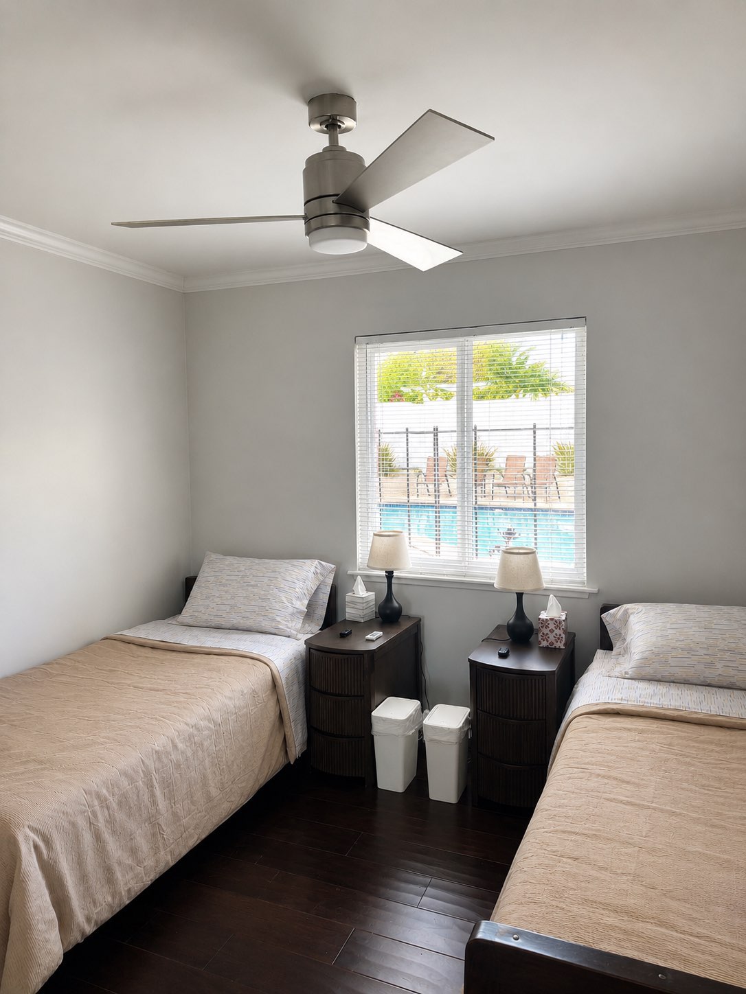 Resident bedroom with two beds and a window overlooking the pool