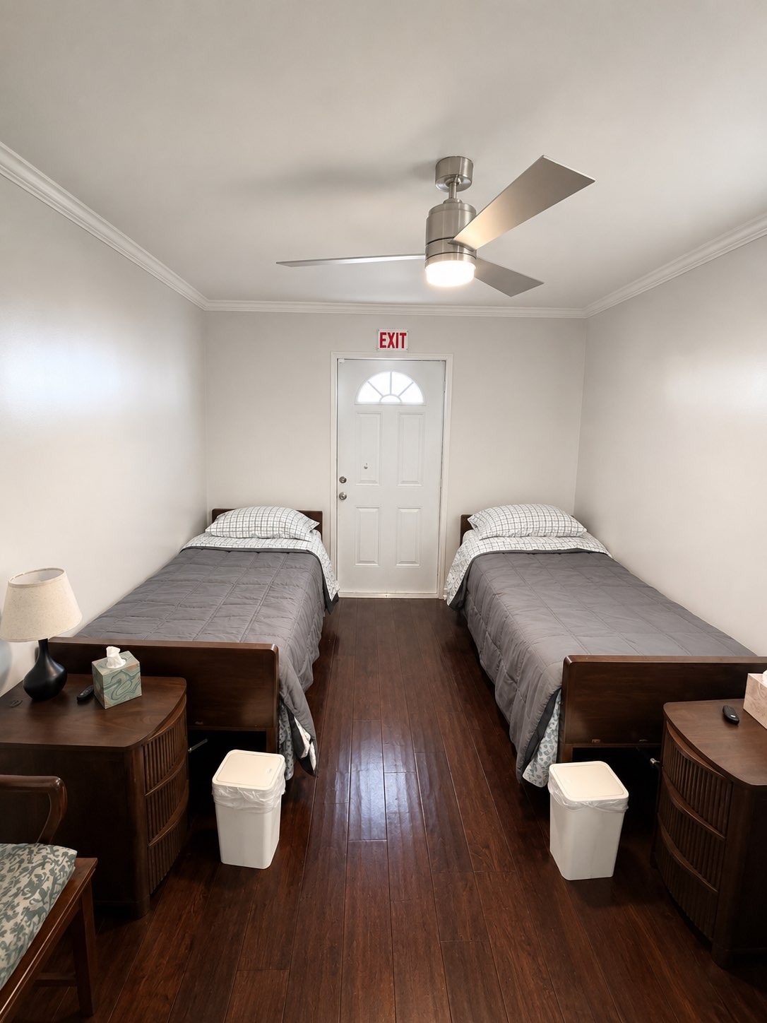 Resident bedroom with two beds and rich wood flooring