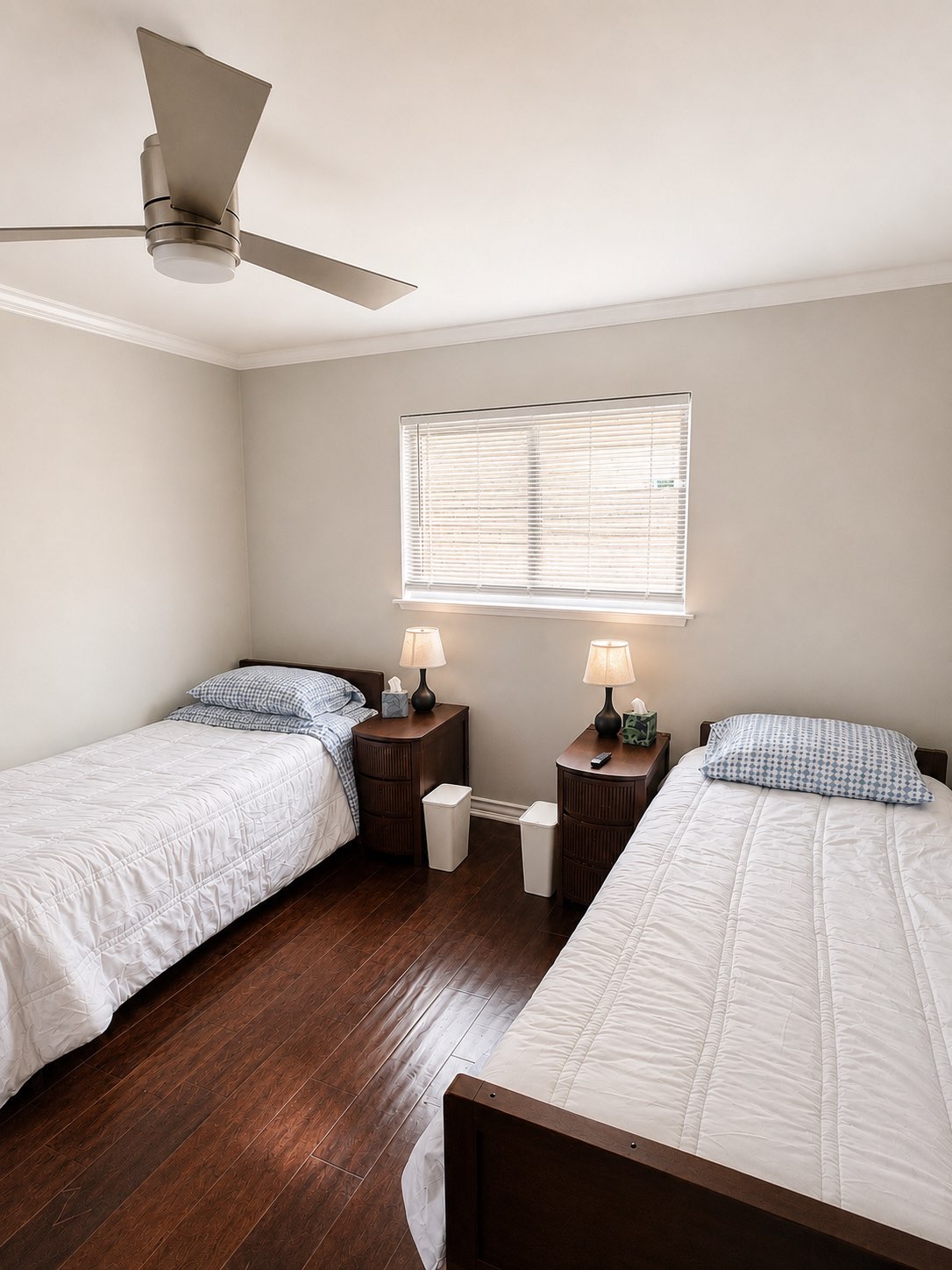 Shared resident bedroom with two twin beds, nightstands, and hardwood flooring